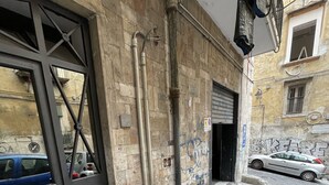 Une entrée d’immeuble avec un portail en métal, un sol carrelé et une voiture garée.