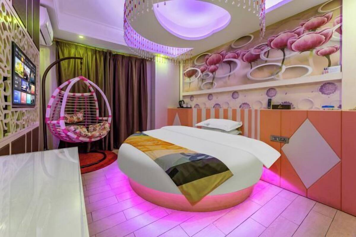 A modern bedroom with a curved bed, a hanging chair, and a wall-mounted TV.
