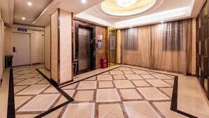 A hotel lobby with a tiled floor, an elevator, and a reception area. - City Boutique Hotel (Heshan Zhongshan Road Xintiandi Branch) (Heshan)