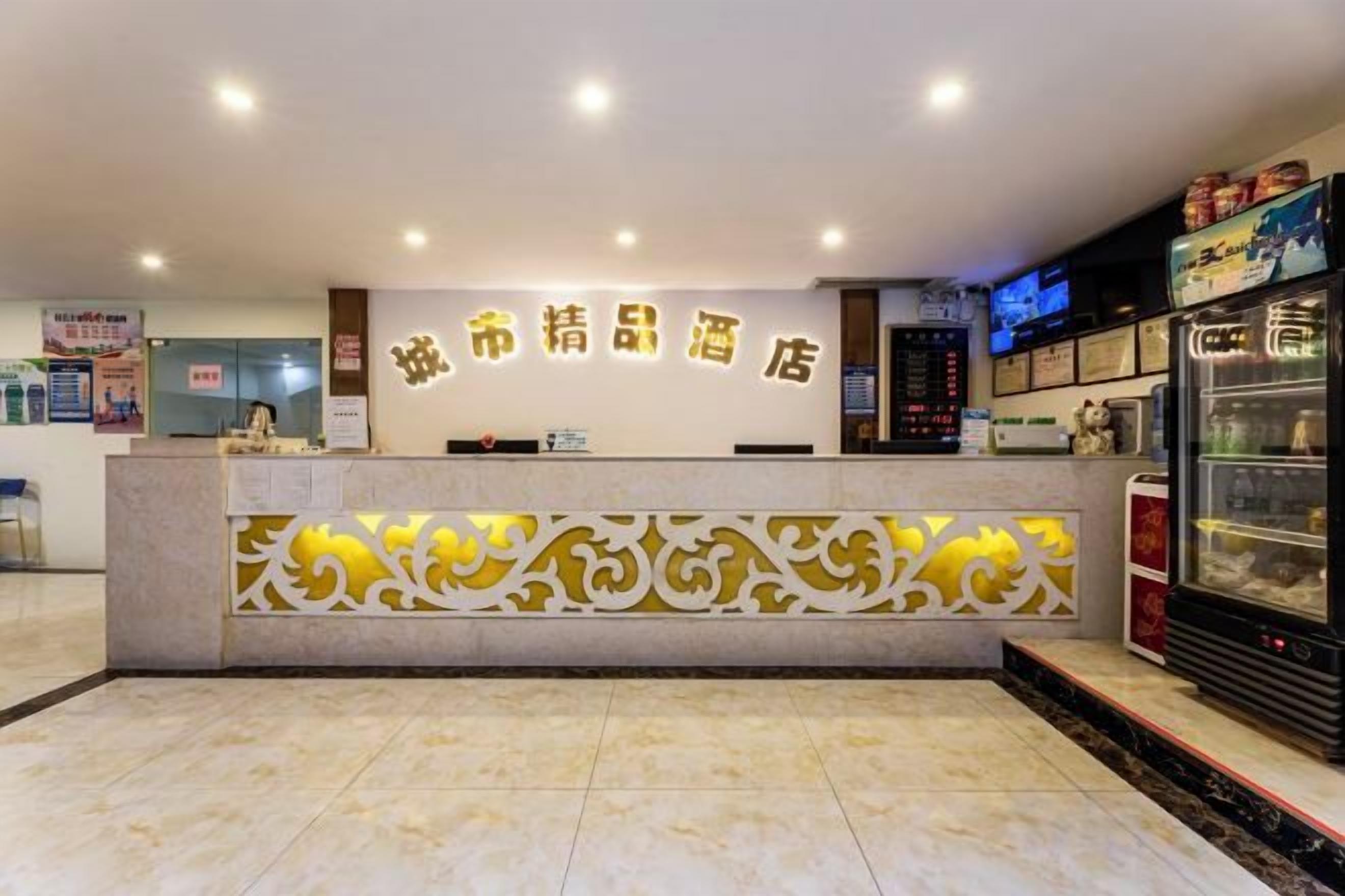 Zona de recepción de un hotel con mostrador, una pared decorativa y un refrigerador.
