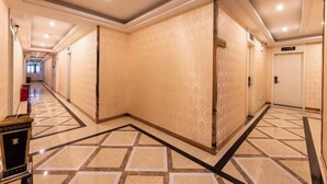 A hotel corridor with patterned flooring, a trash bin, and doors leading to rooms. - City Boutique Hotel (Heshan Zhongshan Road Xintiandi Branch) (Heshan)