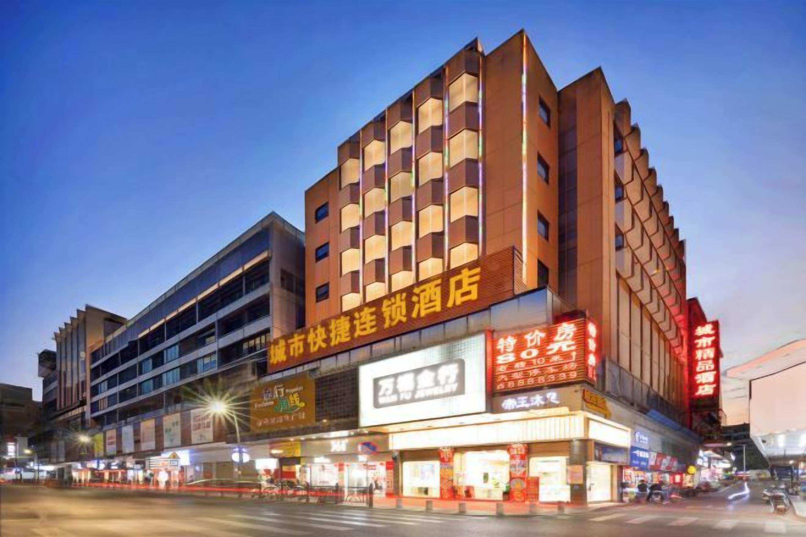 A multi-story hotel with illuminated signage, a prominent entrance, and a street view with other businesses.