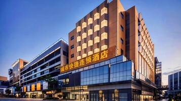 Un hotel de varios pisos con fachada moderna, ventanas grandes y señalización que indica que es un hotel.