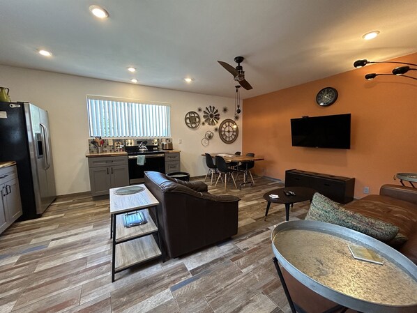 A compact living space with a kitchenette, a dining area, and a seating area with a sofa and a coffee table.