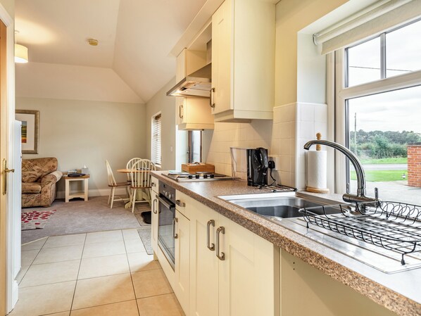 A modern kitchen with a large window, a built-in oven, and a coffee maker. - The Stables - UK36121 (Horsington)