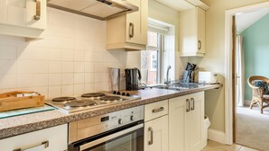 A modern kitchen with white cabinets, a stainless steel stove, and a window providing natural light. - The Stables - UK36121 (Horsington)