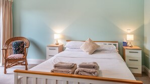 A bedroom with a bed, two bedside tables, a chair, and a window with curtains. - The Stables - UK36121 (Horsington)
