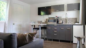 A modern kitchen with a flat-screen TV, a microwave, and a sink. - Le Marigot (Vaudreuil)