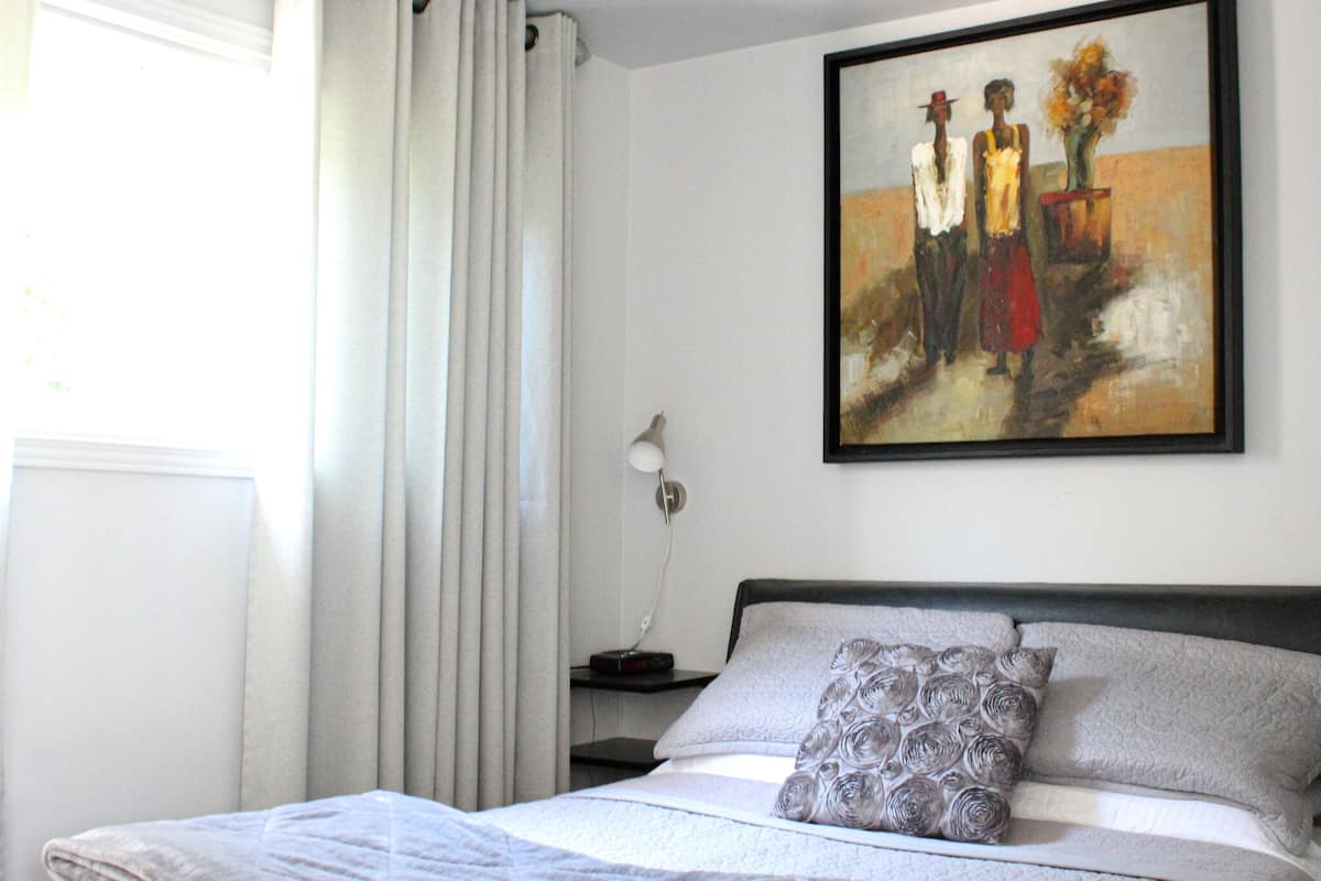 Ein Schlafzimmer mit einem Bett, einem Nachttisch, einer Lampe und einem Gemälde an der Wand.