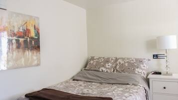 Un dormitorio con una cama, una mesita de noche, una lámpara, un cuadro e indicación de acceso a WiFi.