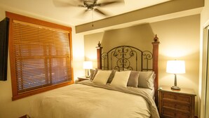 A bedroom with a bed, two bedside tables with lamps, a ceiling fan, and a window with blinds. - Grand Sierra Lodge: Walk to Village Gondola & Ski Back Trail (Mammoth Lakes)