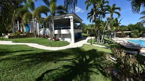 A modern house with a covered porch, surrounded by a well-maintained lawn and palm trees.