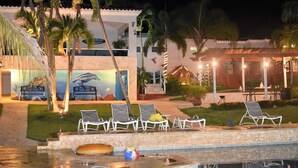 A pool area with lounge chairs, palm trees, and a mural.
