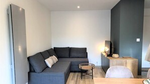 Una sala moderna con un sofá seccional gris, una mesita redonda de mimbre y una mesa de centro de madera.