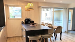 Una cocina moderna con una isla central, taburetes de bar, una cafetera y vistas al exterior.