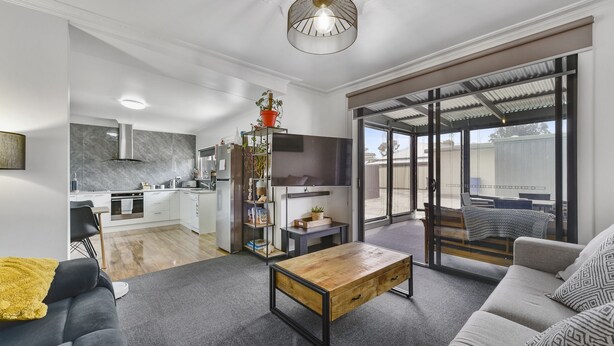 A modern living room with a sofa, coffee table, and a TV mounted on the wall. - Comfort behind Crouch In CBD, newly renovated, perfect for the family & pets (Mount Gambier)