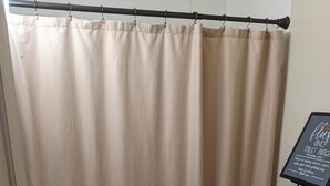 A bathroom with a shower curtain, a sink, a toilet, and a sign on the wall.