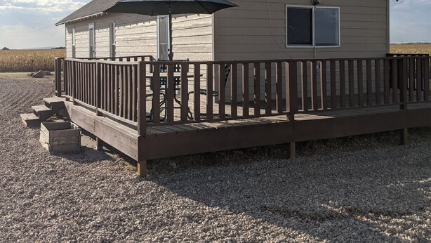 A beach house with a wooden deck, a covered patio, and a view of the ocean.