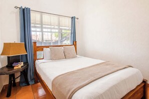A bedroom with a bed, a bedside table with a lamp, and curtains.