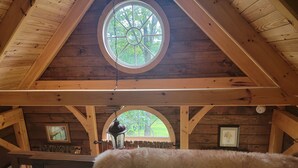 Ein rustikales Holzinterieur mit einem großen, runden Fenster, Holzbalken und einer hängenden Laterne.