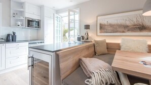 A modern kitchen with white cabinets, a built-in oven, and a large window. - Höög Hüs, Whg. 1 - Höög Hüs (Sylt)