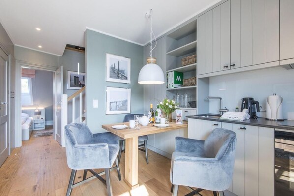 A modern kitchen with grey cabinets, a wooden dining table, and two grey chairs.