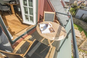 A balcony with a wooden table, chairs, and a magazine.