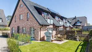 A multi-story house with a sloped roof, brick exterior, and a well-maintained lawn. - Höög Hüs, Whg. 2A - Höög Hüs (Sylt)