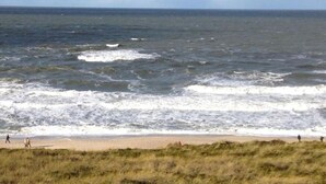 A beach with waves and people walking along the shore. - Höög Hüs, Whg. 2A - Höög Hüs (Sylt)