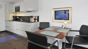 Una cucina moderna con mobili bianchi, un forno a microonde e una zona pranzo con tavolo e sedie.