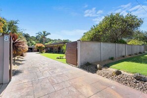 A paved driveway leading to a modern building with a concrete wall and a gate.