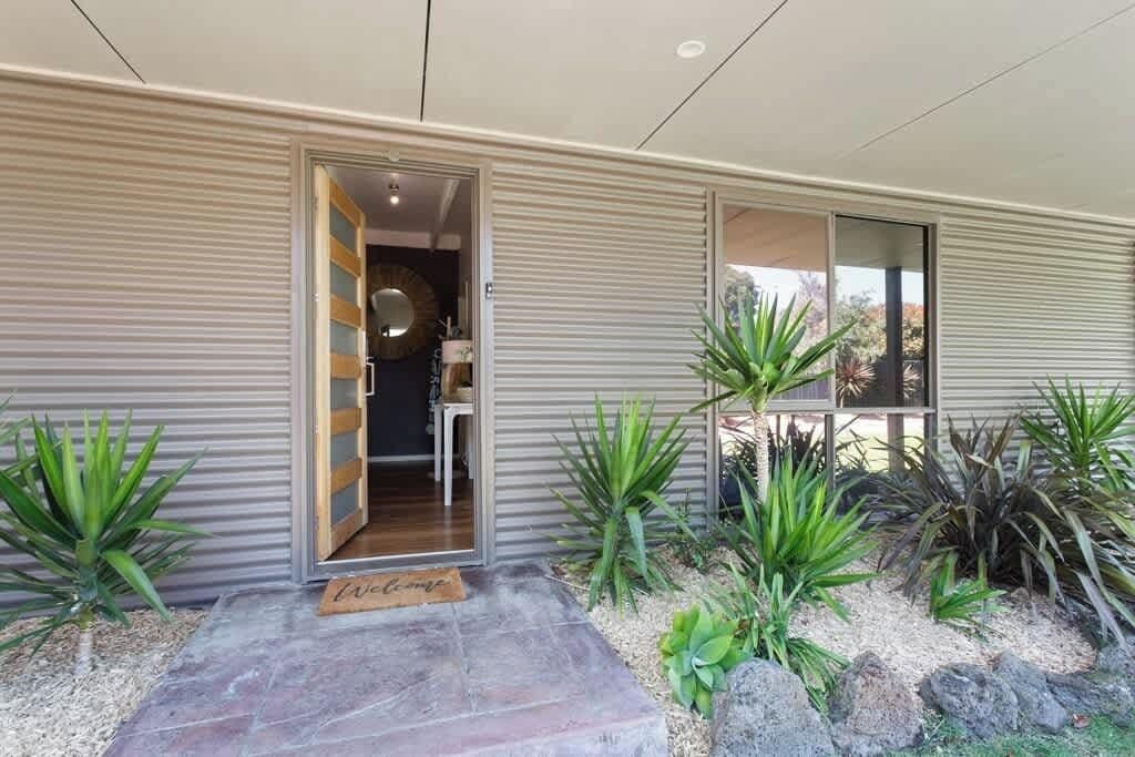 A modern house with a sliding door entrance, a small porch area, and a variety of plants.