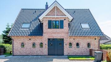 A two-story house with a symmetrical facade, a central entrance, and a sloped roof.