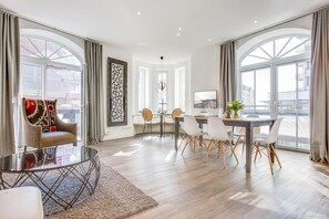 Ein moderner Essbereich mit einem runden Tisch, weißen Stühlen und Blick auf die Stadt durch große Fenster.