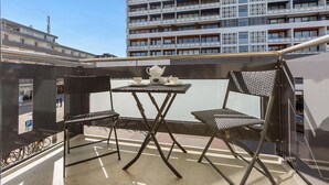 Un balcó amb dues cadires i una taula petita, amb vista a un edifici alt.