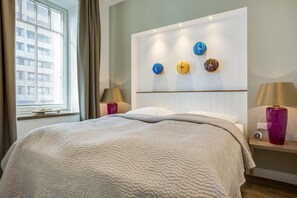 Ein Hotelzimmer mit einem großen Bett, einem Nachttisch mit Lampe und einer Wand mit dekorativen Tellern.