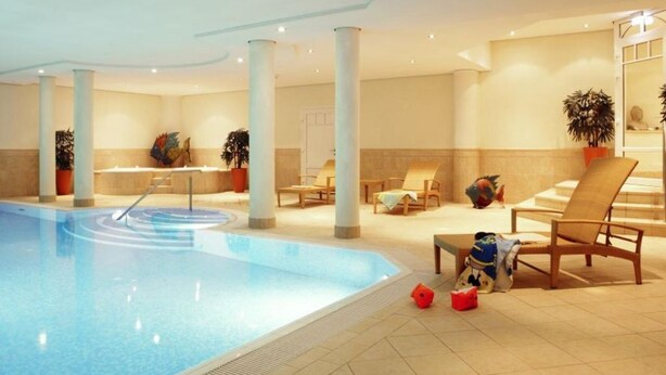 A swimming pool area with lounge chairs, a poolside table, and potted plants. - Residence Bismarck, Whg. 5a - Residence Bismarck (Sylt)