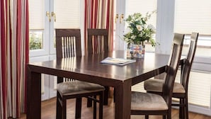 A dining table with four chairs, a vase with flowers, and a magazine on the table.