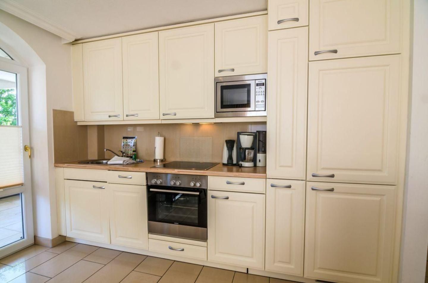 A kitchen with white cabinets, a microwave, a coffee maker, and an oven.