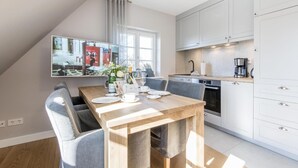Une cuisine moderne avec des meubles blancs, une table à manger avec des chaises et une grande fenêtre.