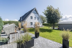 A modern house with a sloped roof, large windows, and a well-maintained lawn.