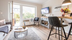 Een moderne woonkamer met een bank, salontafel en een eethoek met stoelen.