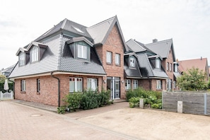 Een rij bakstenen huizen met puntgevels en veel ramen.