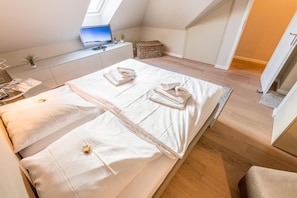 Een moderne, goed verlichte kamer met twee bedden, een klein bureau en uitzicht op het landschap door een dakraam.