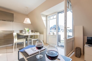 Een moderne keuken met een eethoek, een glazen deur naar een balkon en een televisie op een kast.