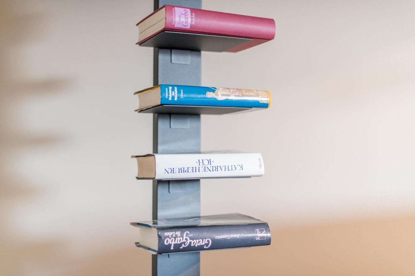 A vertical stack of books on a gray stand.