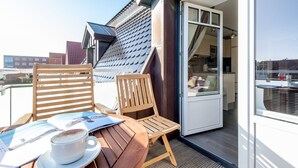 A balcony with two wooden chairs, a table, and a cup of coffee. - House Nordmarkgarten, Whg. 7 - House Nordmarkgarten (Sylt)