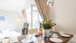 A dining area with a table set for two, a vase of flowers, and a modern lamp. - House Nordmarkgarten, Whg. 7 - House Nordmarkgarten (Sylt)