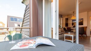 A balcony with a table, a glass of wine, and a magazine. - House Hauke, Whg. 8 - House Hauke (Sylt)