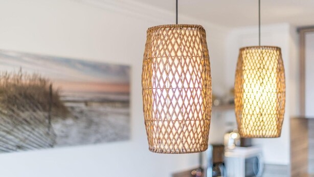 Två flätade hänglampor hänger i ett modernt kök, med en mikrovågsugn och en tavla i bakgrunden.